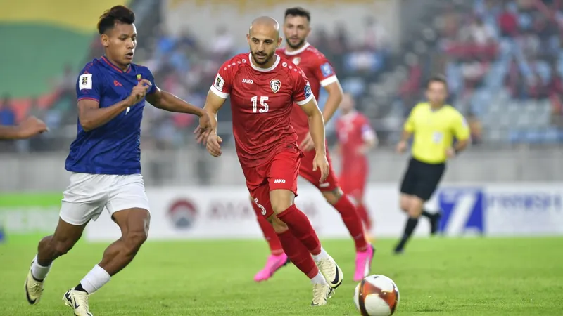 Cầu thủ Myanmar dẫn bóng qua cầu thủ Syria trong trận đấu bóng đá